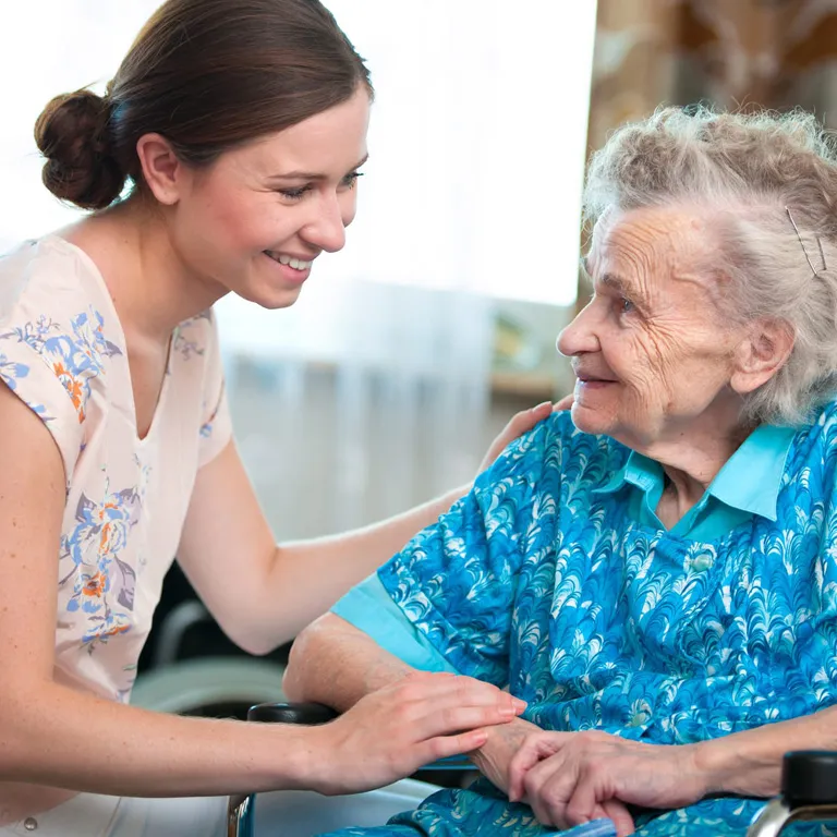 Team member interacting with Resident sitting in a chair.