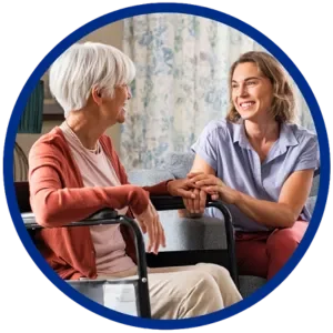 Team member holding the hand of a Resident sitting in a chair.